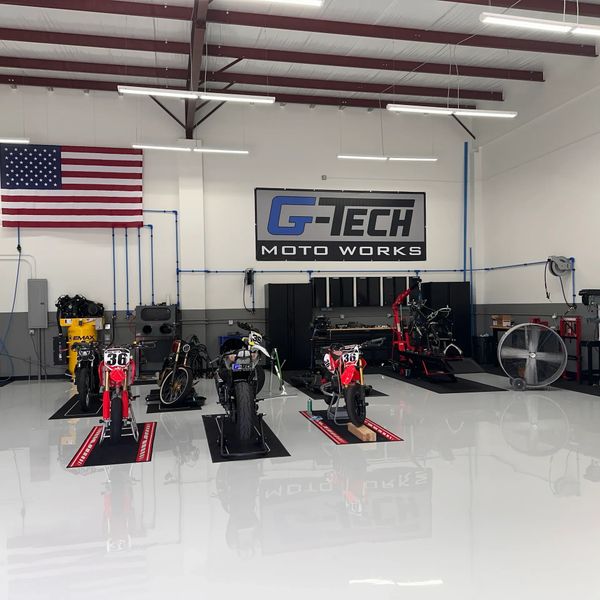 A clean motorcycle workshop with several bikes and an American flag.