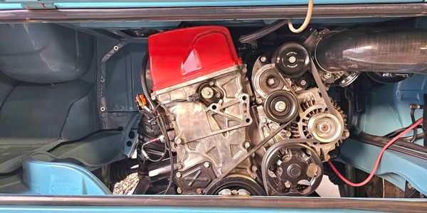 Close-up of a car engine with a red cover inside a blue engine bay.