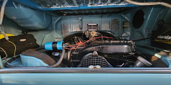 Classic car engine bay with clean, vintage components and blue accents.
