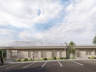 Modern single-story building with parking spaces and cloudy sky.