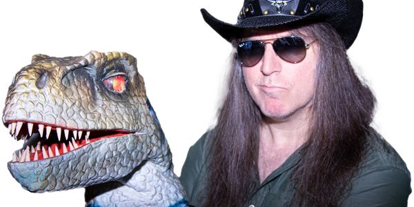 Man with long hair and sunglasses posing with a dinosaur puppet.