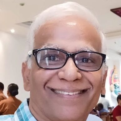 Smiling elderly man with white hair and glasses.