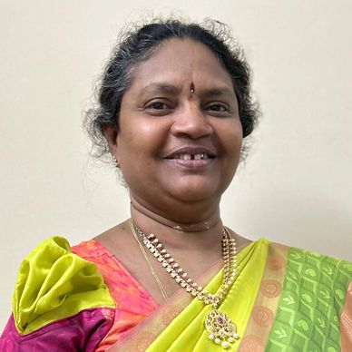 A smiling woman in a traditional colorful saree.
