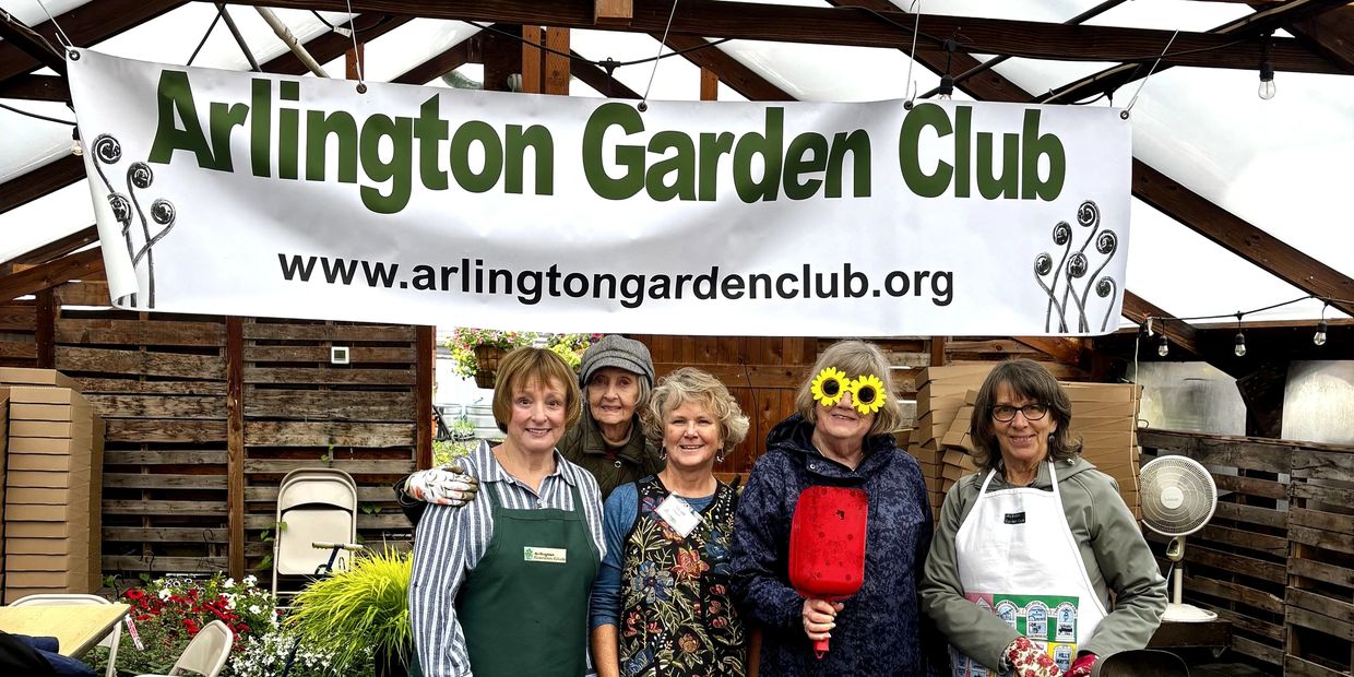 Five women stand under an Arlington Garden Club banner.