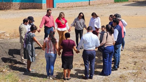 A group of people holding hands in a circle outdoors.