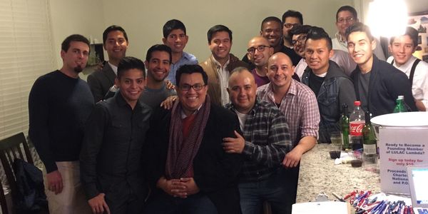 Group of men gathered indoors around a counter.