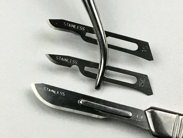 Three types of surgical blades used for dermaplaning one is on a metal handle