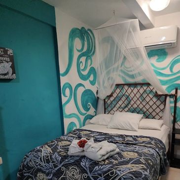 Cozy bedroom with ocean-themed mural and net canopy bed.