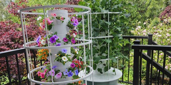 A vertical garden tower filled with colorful flowers on a balcony.