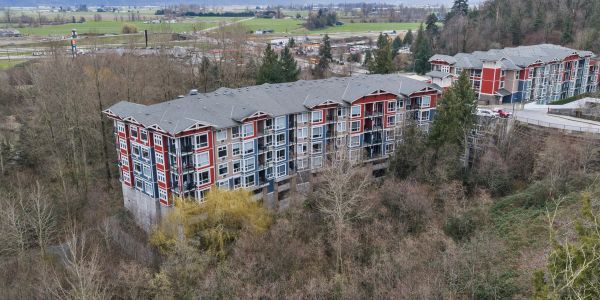 Large apartment buildings near a wooded area.
