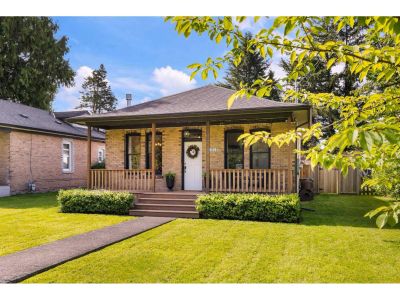 Charming brick house with a front porch and well-maintained lawn.