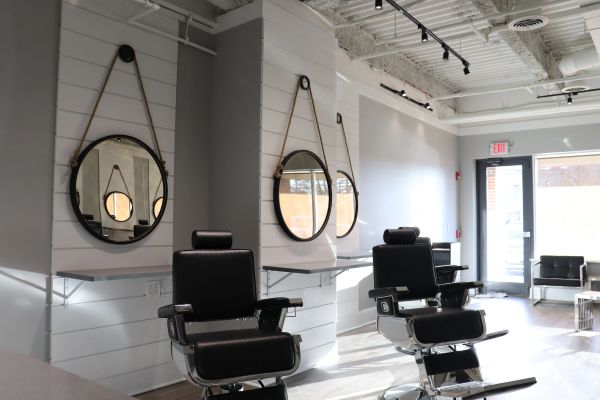 Modern barbershop with black leather chairs and round mirrors.