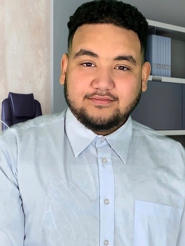 Smiling man in a light blue button-up shirt indoors.