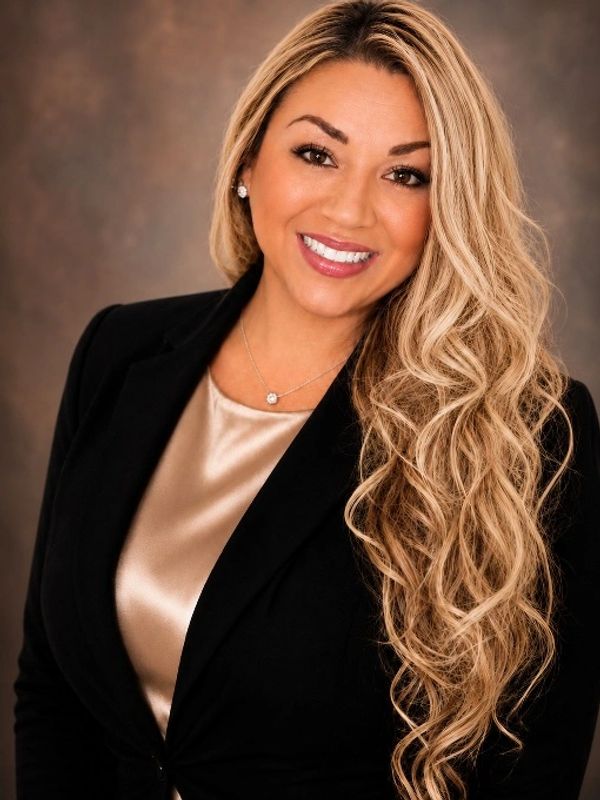 Smiling woman with long curly blonde hair in business attire.