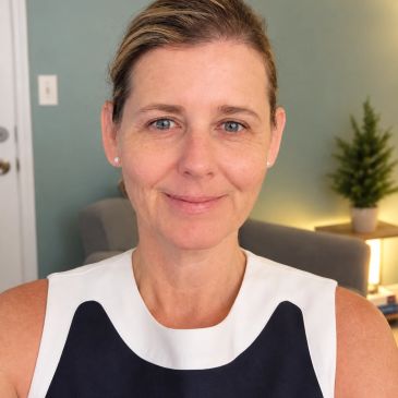 Woman smiling indoors with a blurred background.