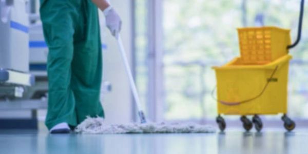 Person mopping floor with mop and yellow bucket nearby.
