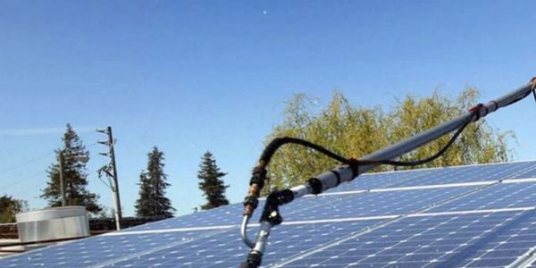 Solar panels on a sunny day with a cleaning device attached.