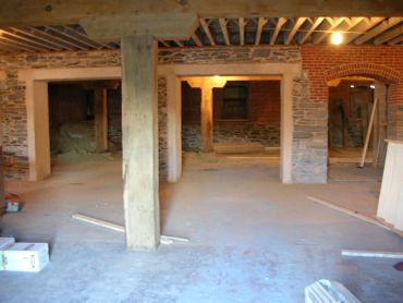 Interior of a building under renovation with exposed brick and concrete pillars.