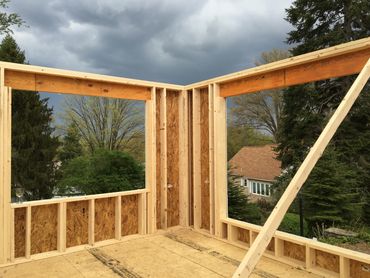 Wooden framed walls under construction with a cloudy sky.