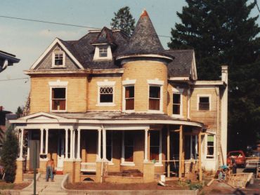 A large, old Victorian house with a turret and wraparound porch.