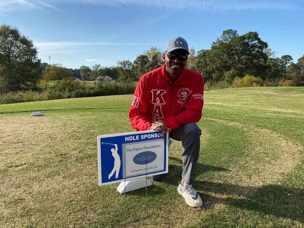 Man kneeling next to sign and smiling