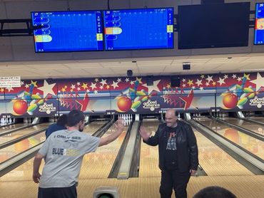 Two men at a bowling alley exchanging a high five.