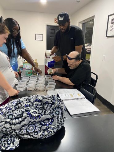 Group of people preparing cups of food or drink together.