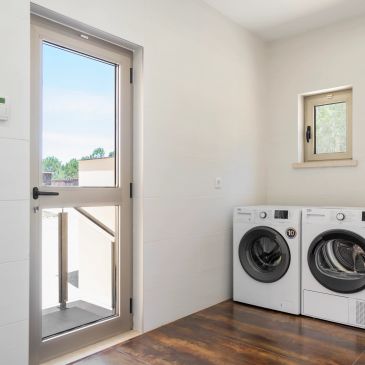 Modern laundry room with washer, dryer, and glass door.