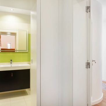 Modern bathroom with green tiles and white doors.
