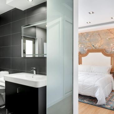 View of a modern bathroom and bedroom separated by a frosted glass door.