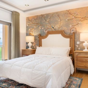 Cozy bedroom with floral wallpaper and elegant wooden furniture.