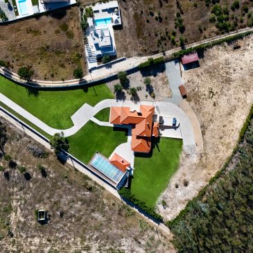 Aerial view of a house with a red roof and green yard.