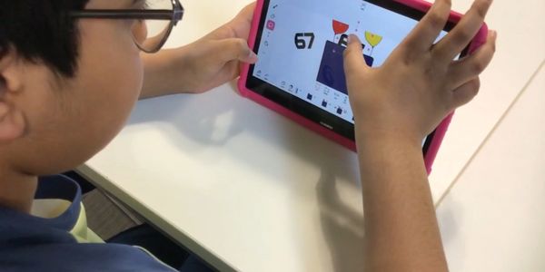 Child using a tablet for a digital drawing or game involving trophies.