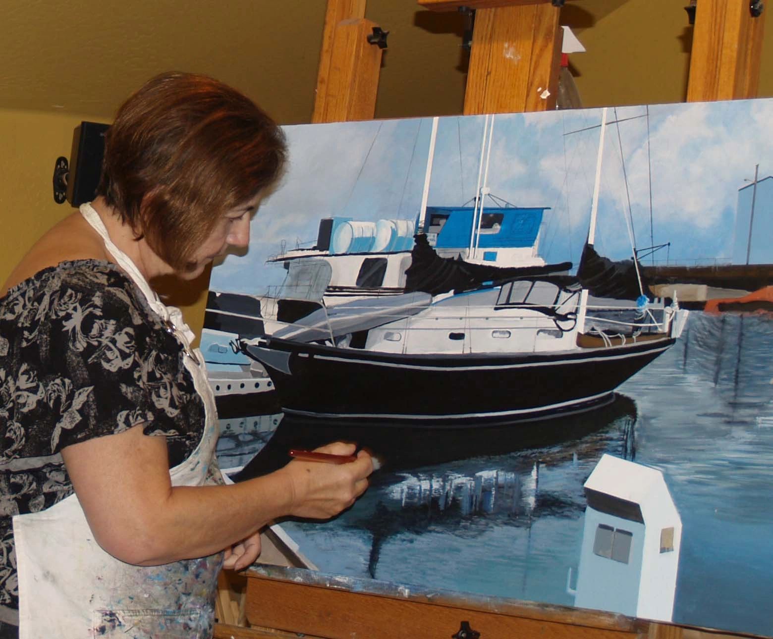 A brunette woman in an apron painting a boat