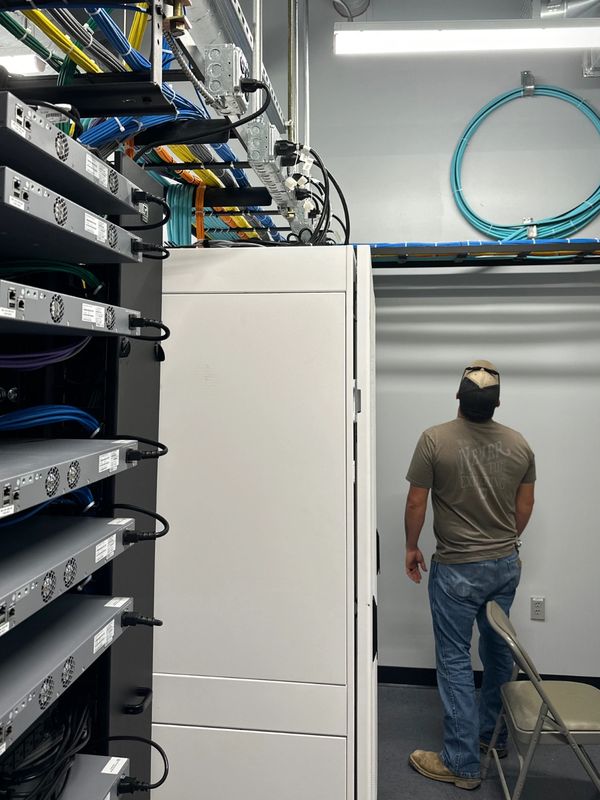 Technician working in a server room filled with network cables and equipment.