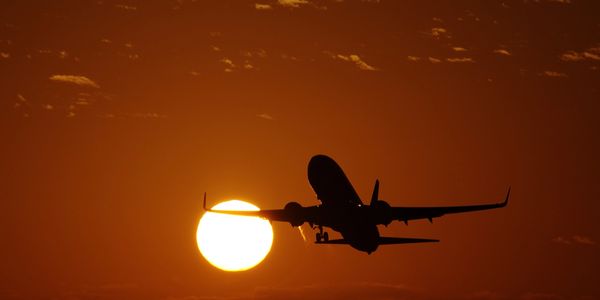Silhouette of airplane flying during sunset.