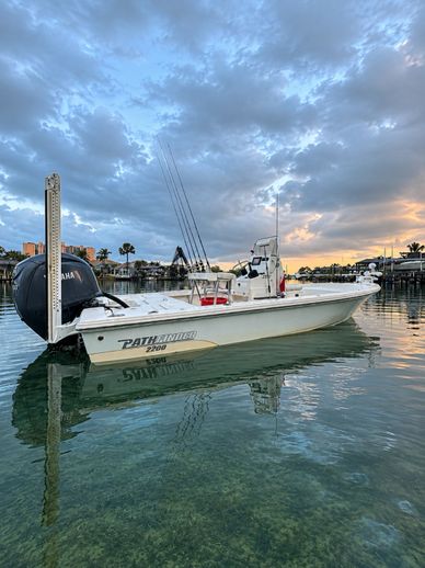 A white PathFinder fishing boat docked on calm water at sunset.