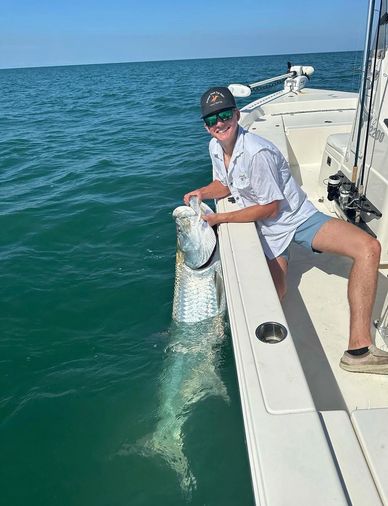 Young man on boat holding a huge fish in the water.