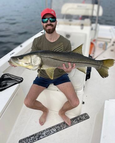 Man in sunglasses holding a large fish on a boat.