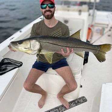Man in sunglasses holding a large fish on a boat.