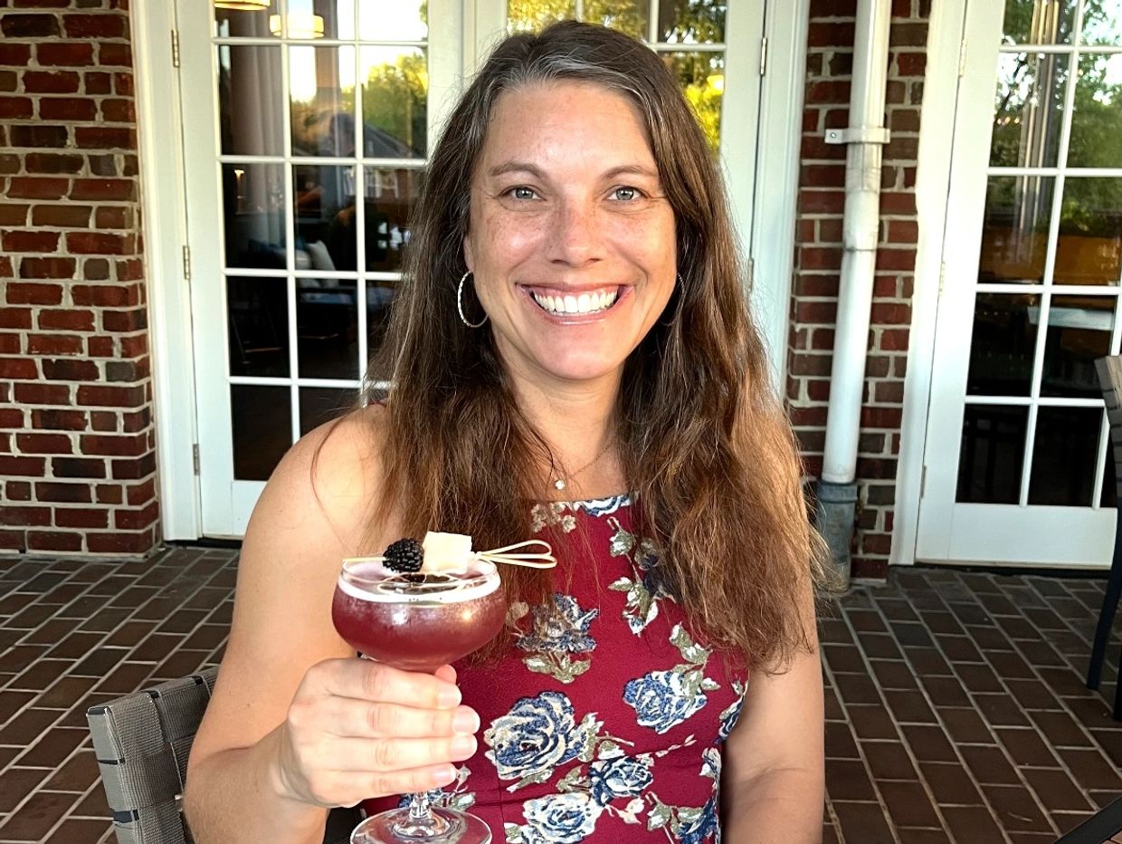 Smiling woman holding a red cocktail indoors.