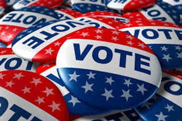 A pile of patriotic red, white, and blue "VOTE" buttons with stars.