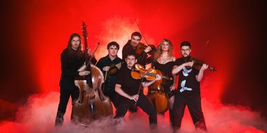 A six-member string band posing with instruments against a red smoky background.