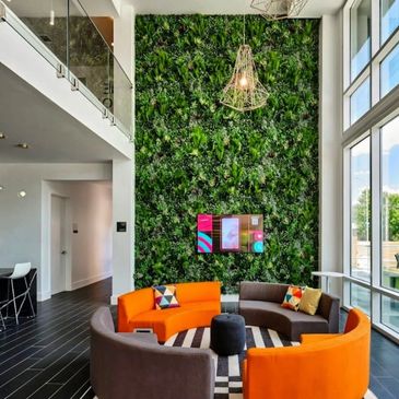 Modern lounge with circular sofas and green plant wall.