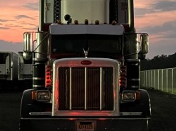 Front view of a semi-truck at sunset with dramatic lighting.