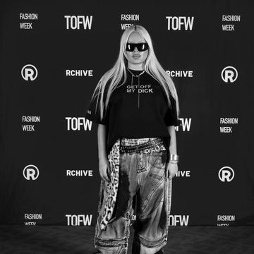 Person with long hair and sunglasses at a fashion event.