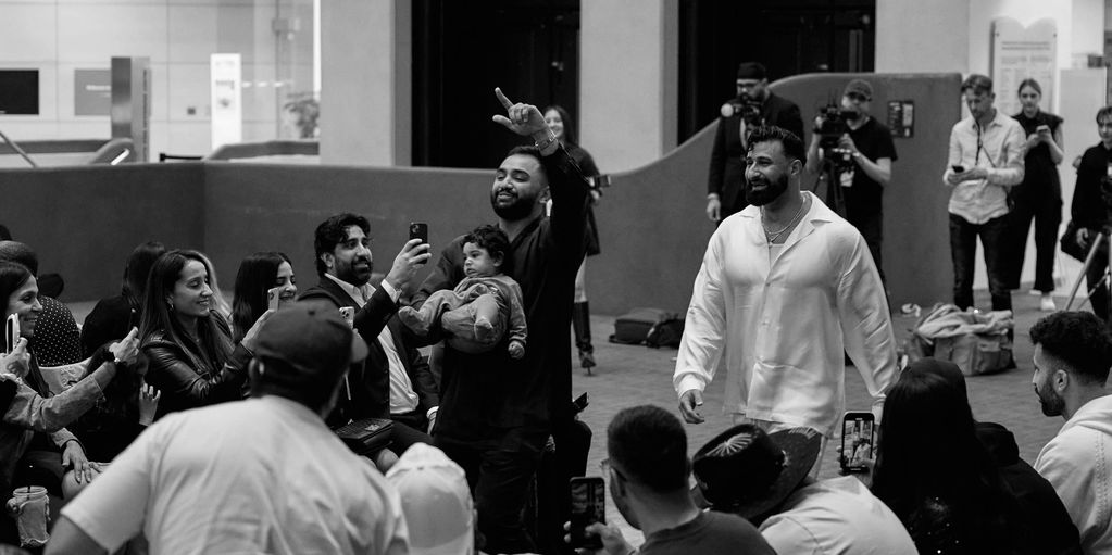 A man confidently walks among a crowd capturing moments on their phones.