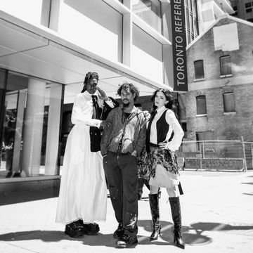 Three stylish individuals posing confidently on a sunny city street near Toronto Reference Library.