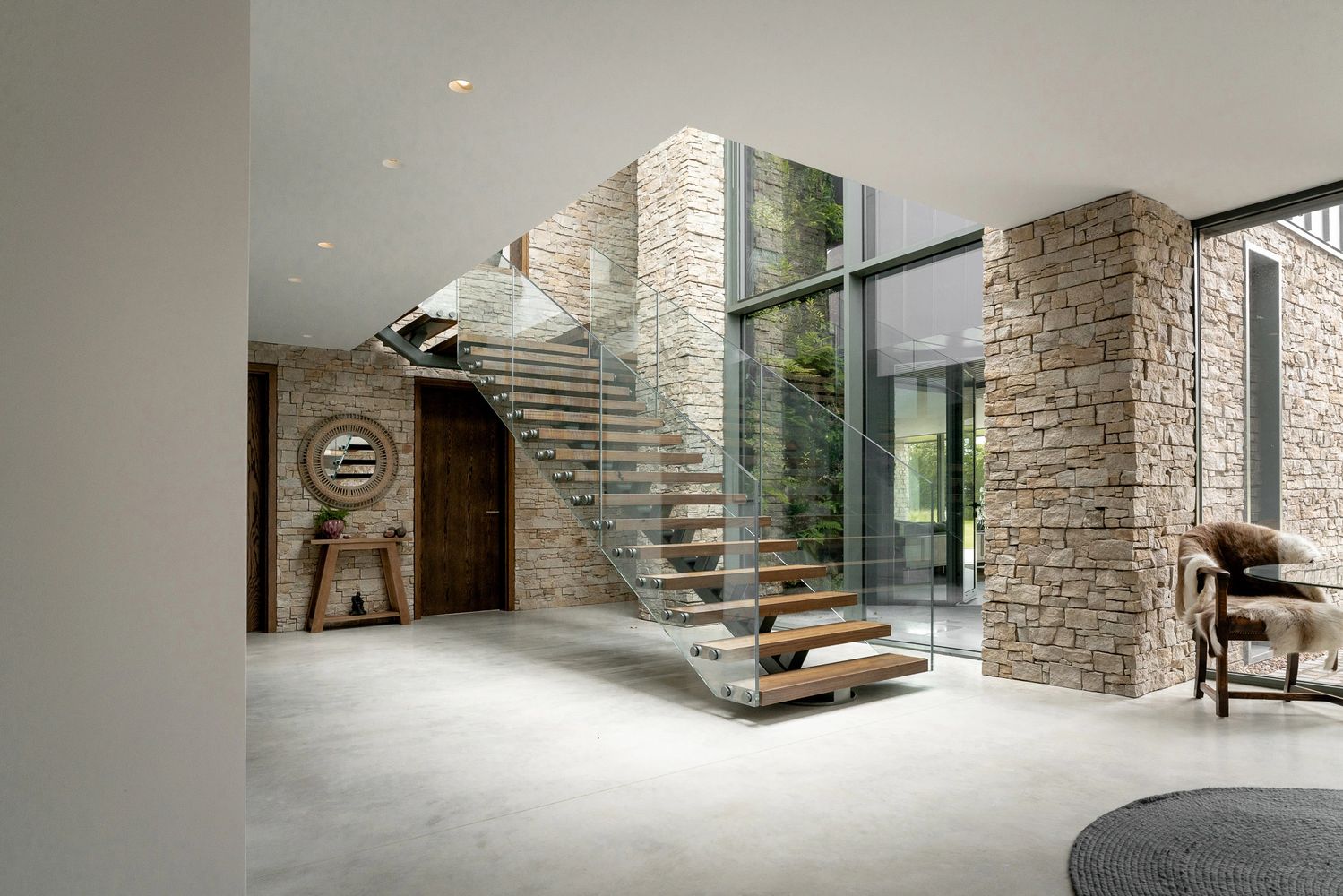 Contemporary entrance hallway with a concrete floor, floating staircase and stone walls, modern