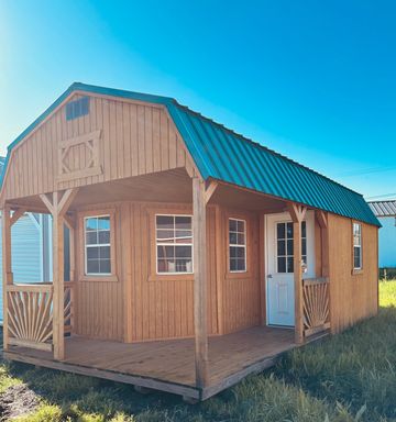 Wooden cabin with a green metal roof under a clear blue sky.